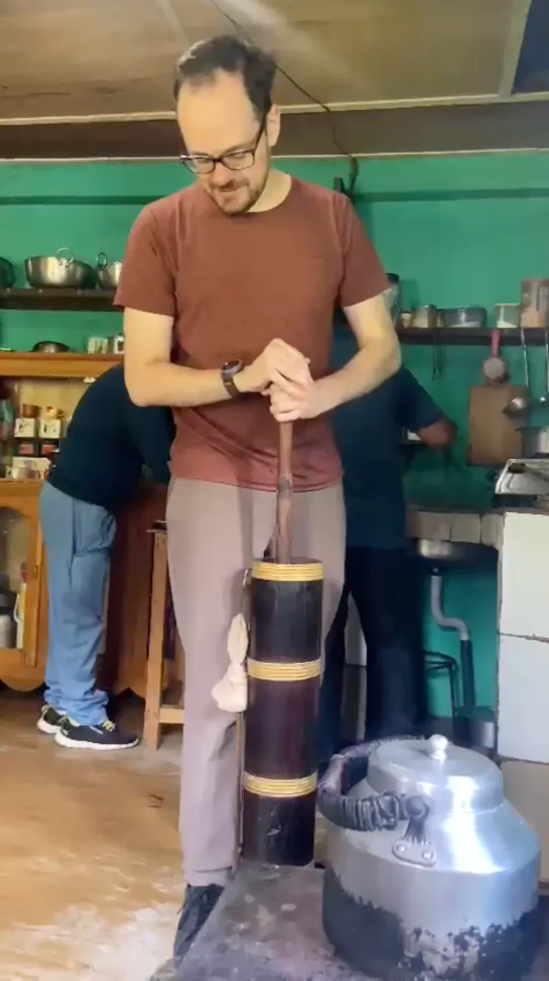 A traveler making traditional butter tea by hand